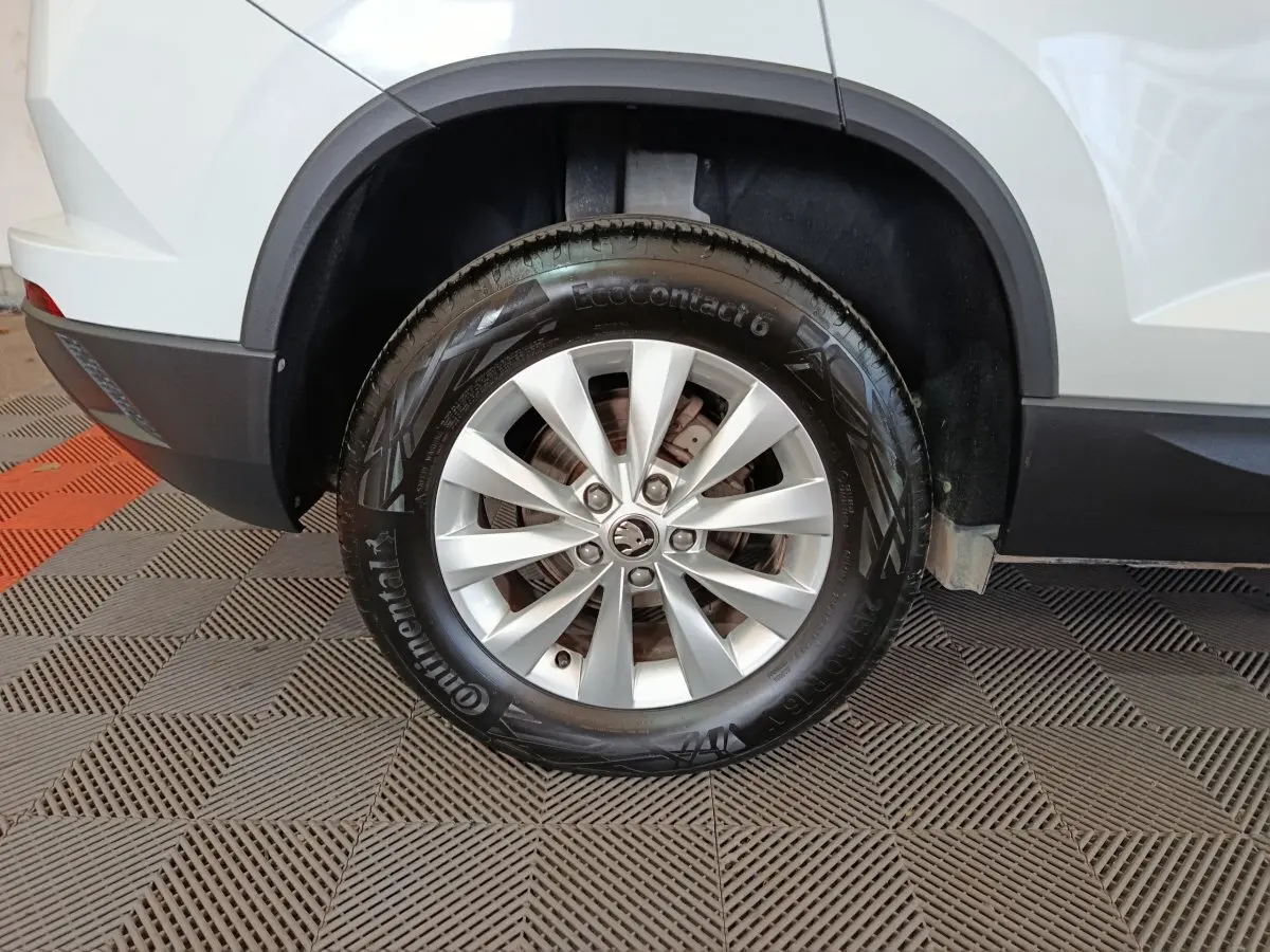 Gros plan sur la roue arrière droite argentée d'un Skoda Karoq blanc avec jante en alliage et pneu Continental.