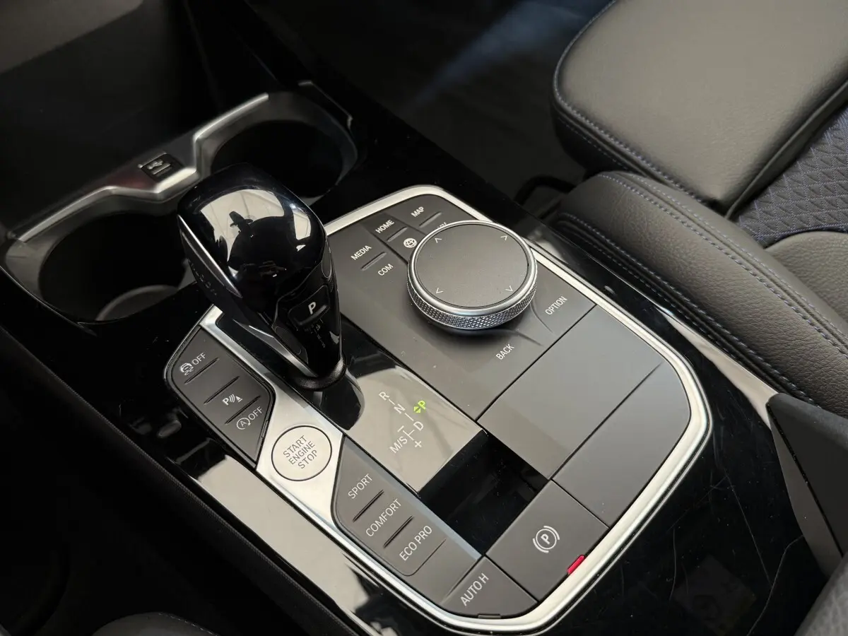 Gros plan sur la console centrale noire de la BMW Série 1 120i Edition M Sport Pro avec levier de vitesses et molette de contrôle.