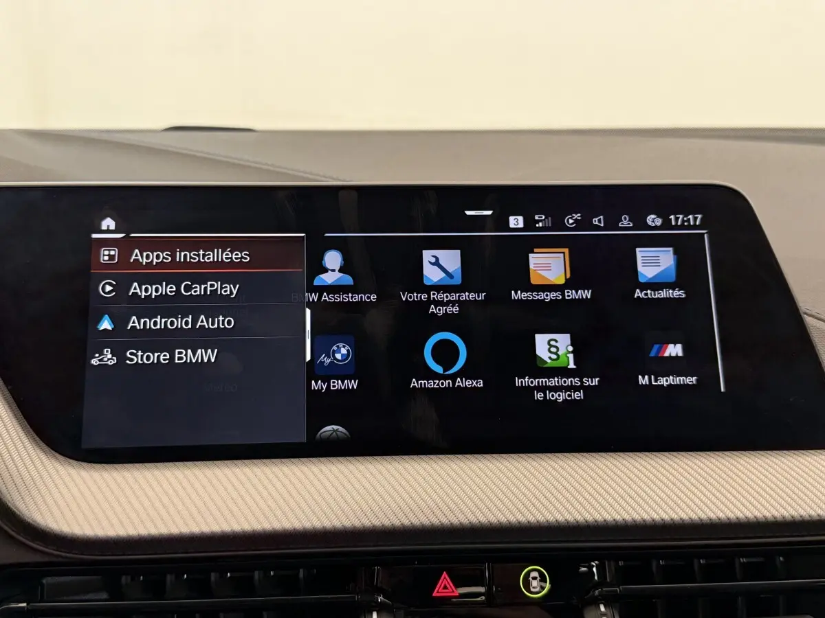 Écran tactile central affichant les applications connectées dans l’habitacle beige d’une BMW Série 1 noire.