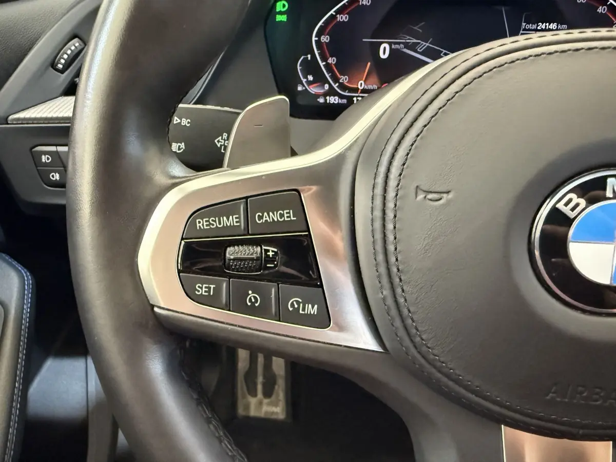 Gros plan sur le volant cuir noir de BMW Série 1 120i Edition M Sport Pro avec commandes multifonctions côté gauche.