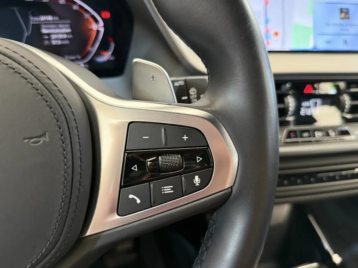 Gros plan sur les commandes multifonctions du volant cuir noir d’une BMW Série 1 120i Edition M Sport Pro 2023.
