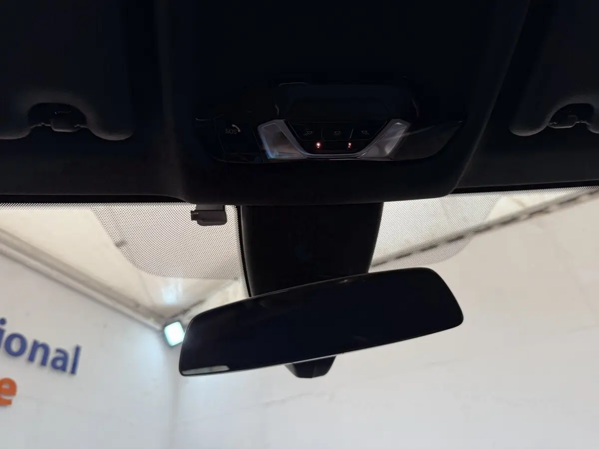 Vue intérieure centrée sur le rétroviseur intérieur et la console de plafonnier d’une BMW Série 1 noire.