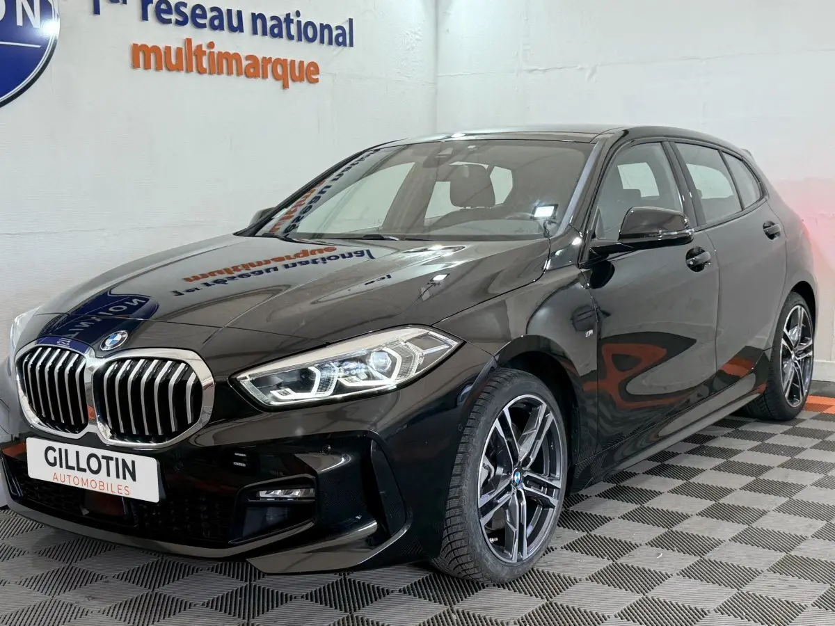BMW Série 1 noire en 3/4 avant droit, avec calandre chromée et jantes alliage distinctives M Sport Pro.