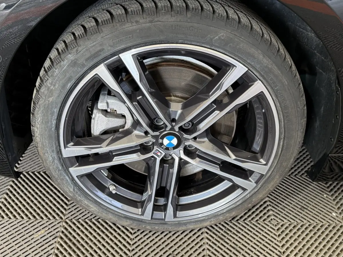 Gros plan sur la roue avant droite de la BMW Série 1 120i Edition M Sport Pro noire, jante alliage M distinctive.