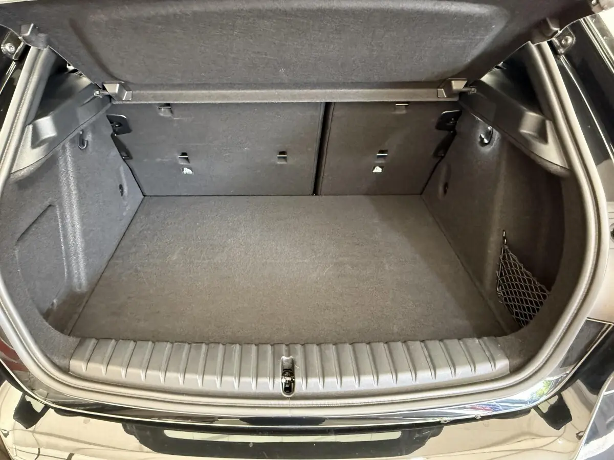 Coffre ouvert de BMW Série 1 120i noir, vue arrière, montrant un espace de chargement propre et spacieux.
