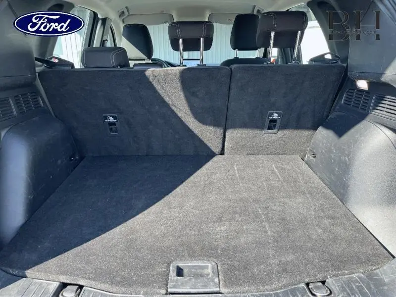 Coffre spacieux du Ford Kuga 2022 gris métallisé vu de l'arrière avec banquette arrière noire en tissu relevée.