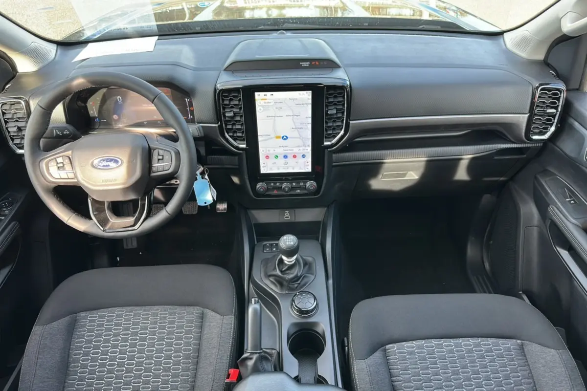Vue intérieure frontale du Ford Ranger 2026, tableau de bord noir avec écran tactile vertical et volant multifonctions.
