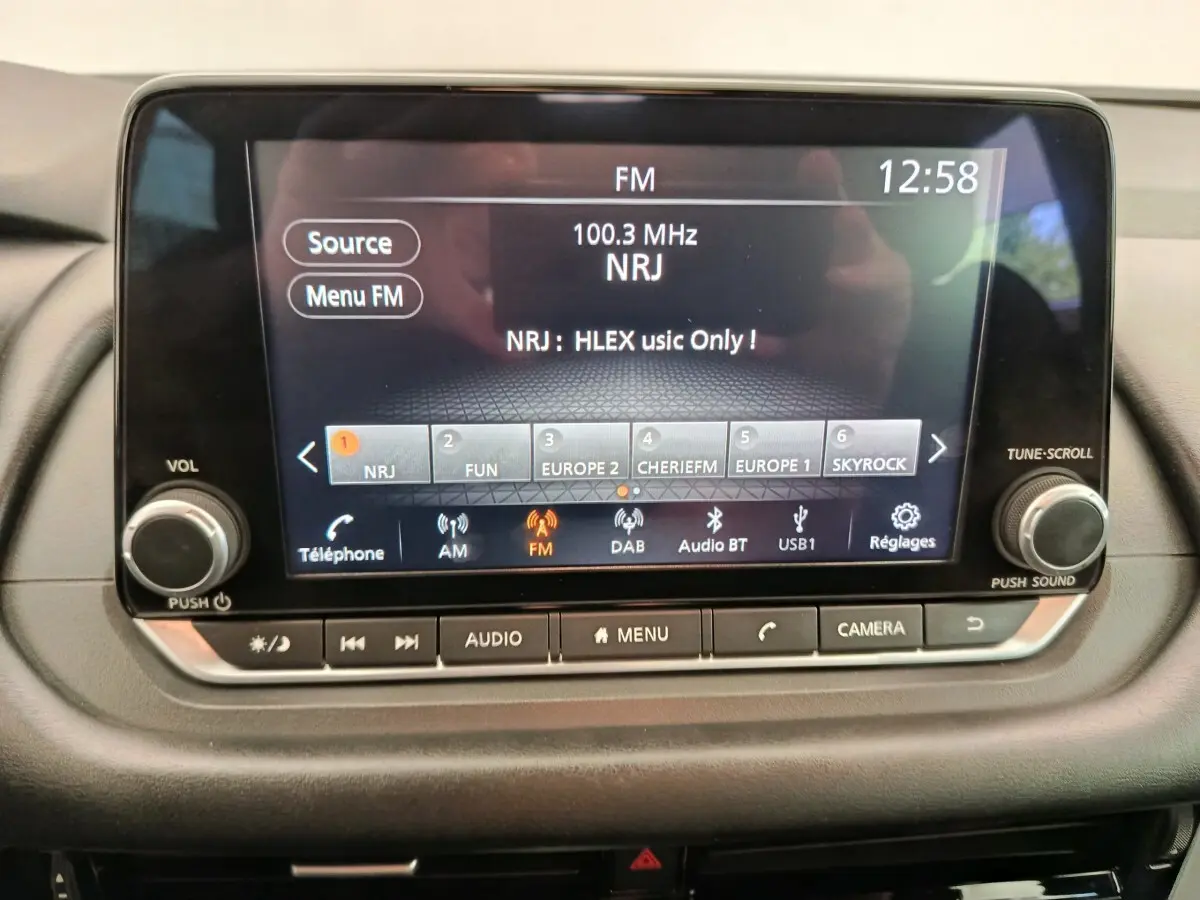 Écran tactile central du tableau de bord du Nissan Qashqai e-Power 2024 affichant la radio FM NRJ à 12h58.
