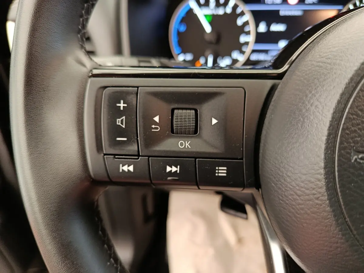 Gros plan sur les commandes multifonctions noires à gauche du volant cuir du Nissan Qashqai e-Power 2024.