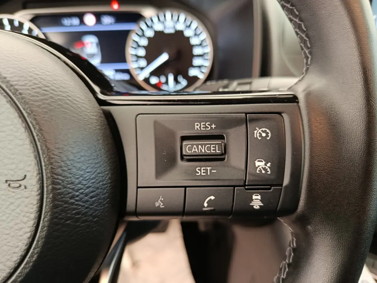 Gros plan sur les commandes du régulateur de vitesse au volant cuir noir du Nissan Qashqai e-Power 2024.