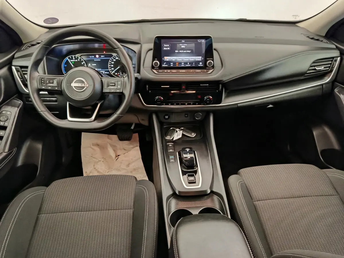 Vue intérieure avant du Nissan Qashqai e-Power 190 Business Edition 2024, tableau de bord noir avec écran tactile central et volant multifonctions.