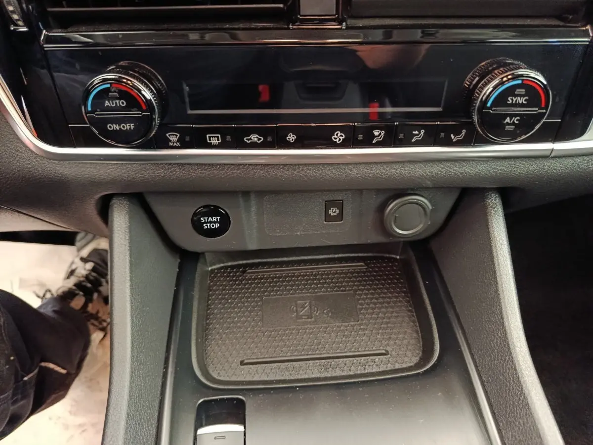Gros plan sur la console centrale noire du Nissan Qashqai e-Power 2024 avec commandes climatisation et bouton start/stop.