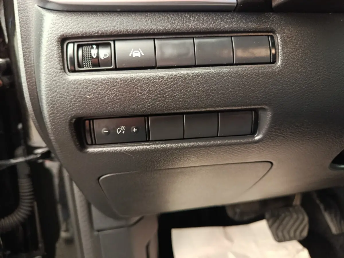 Vue rapprochée des commandes de réglage d’éclairage et d’aide à la conduite sur le tableau de bord noir du Nissan Qashqai e-Power 2024.