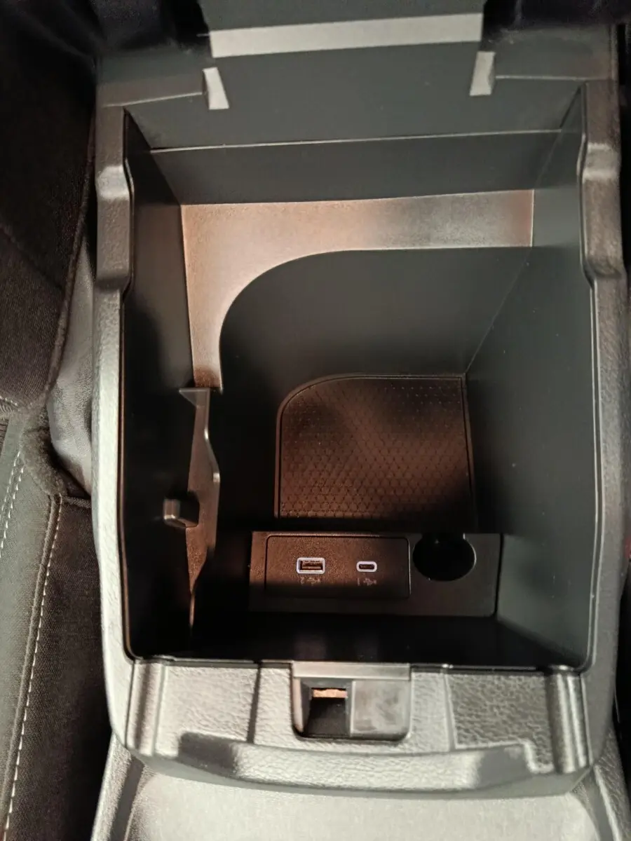 Vue plongeante sur le rangement central noir du Nissan Qashqai e-Power 2024 avec ports USB et prise 12V intégrés.