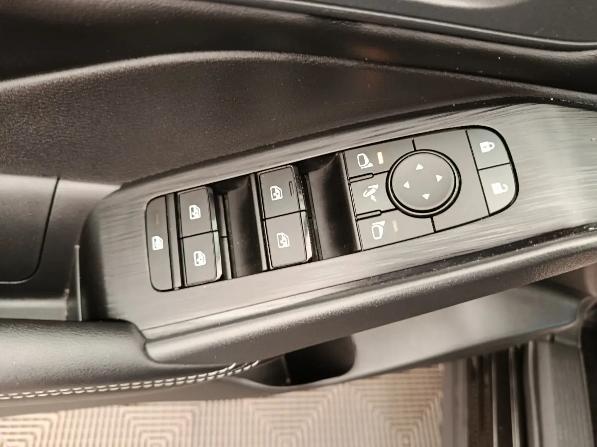 Gros plan sur les commandes de lève-vitres et rétroviseurs côté conducteur du Nissan Qashqai e-Power noir 2024.