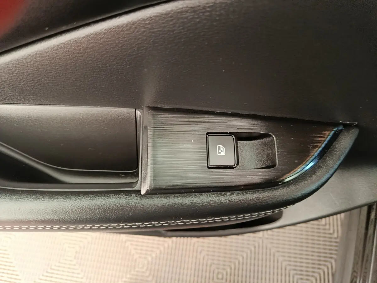 Détail de la commande de lève-vitre électrique sur la porte intérieure côté conducteur du Nissan Qashqai noir 2024.