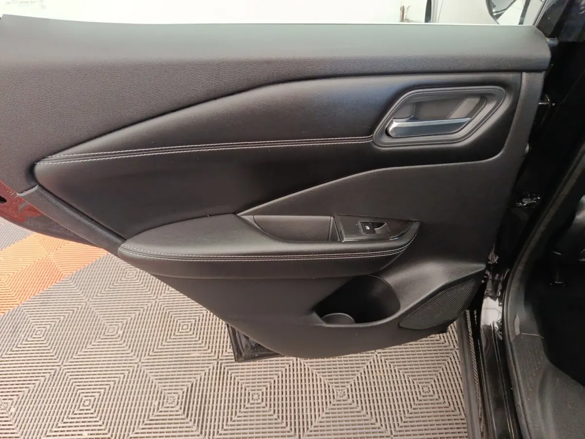 Vue rapprochée de la porte intérieure côté conducteur noire du Nissan Qashqai e-Power 2024 avec poignée et commande de lève-vitre.