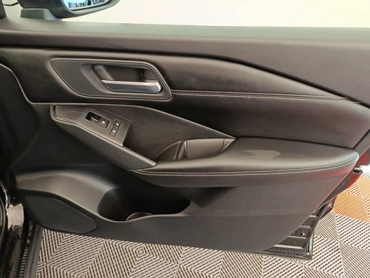 Gros plan sur la porte avant gauche noire du Nissan Qashqai e-Power 2024 avec commandes de lève-vitres et poignée intégrée.