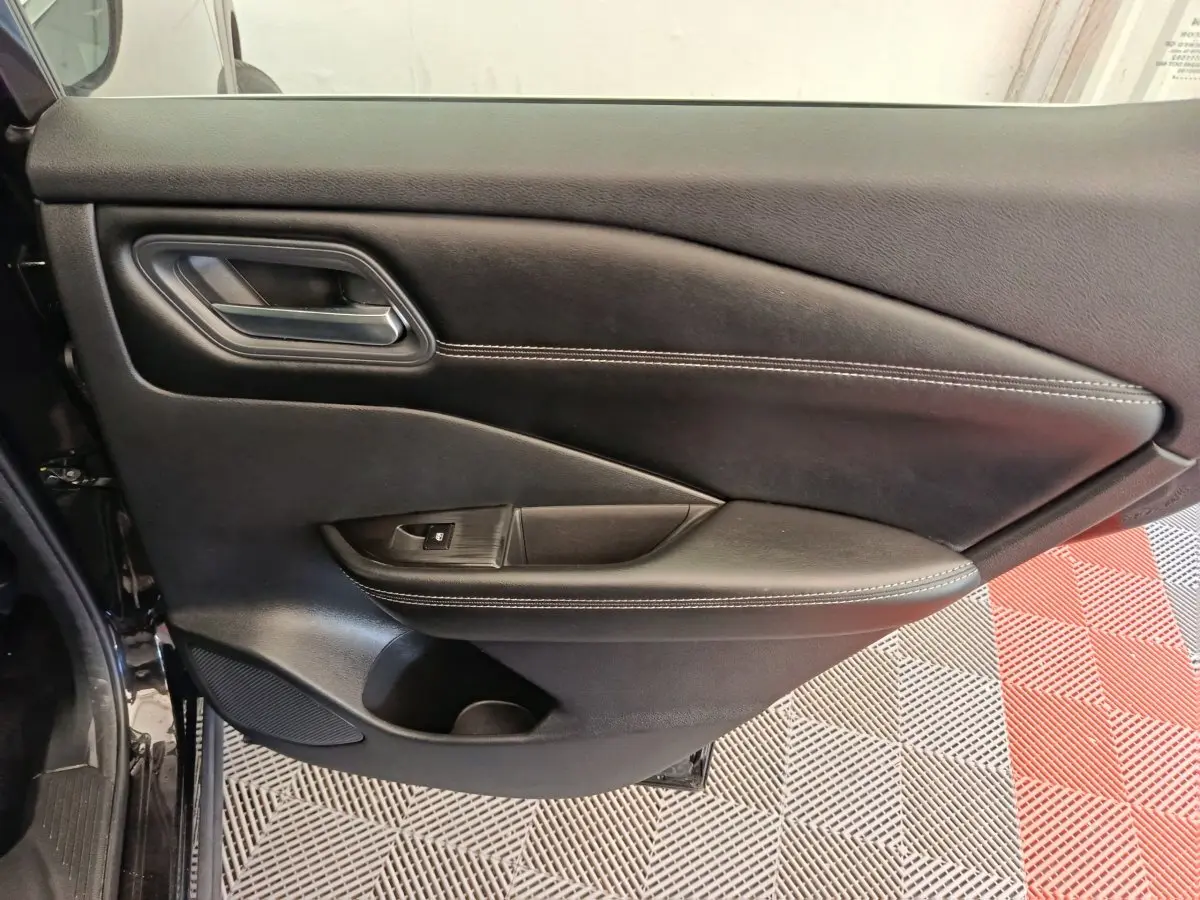 Gros plan sur la porte arrière gauche noire du Nissan Qashqai e-Power 190 Business Edition 2024 avec surpiqûres blanches.