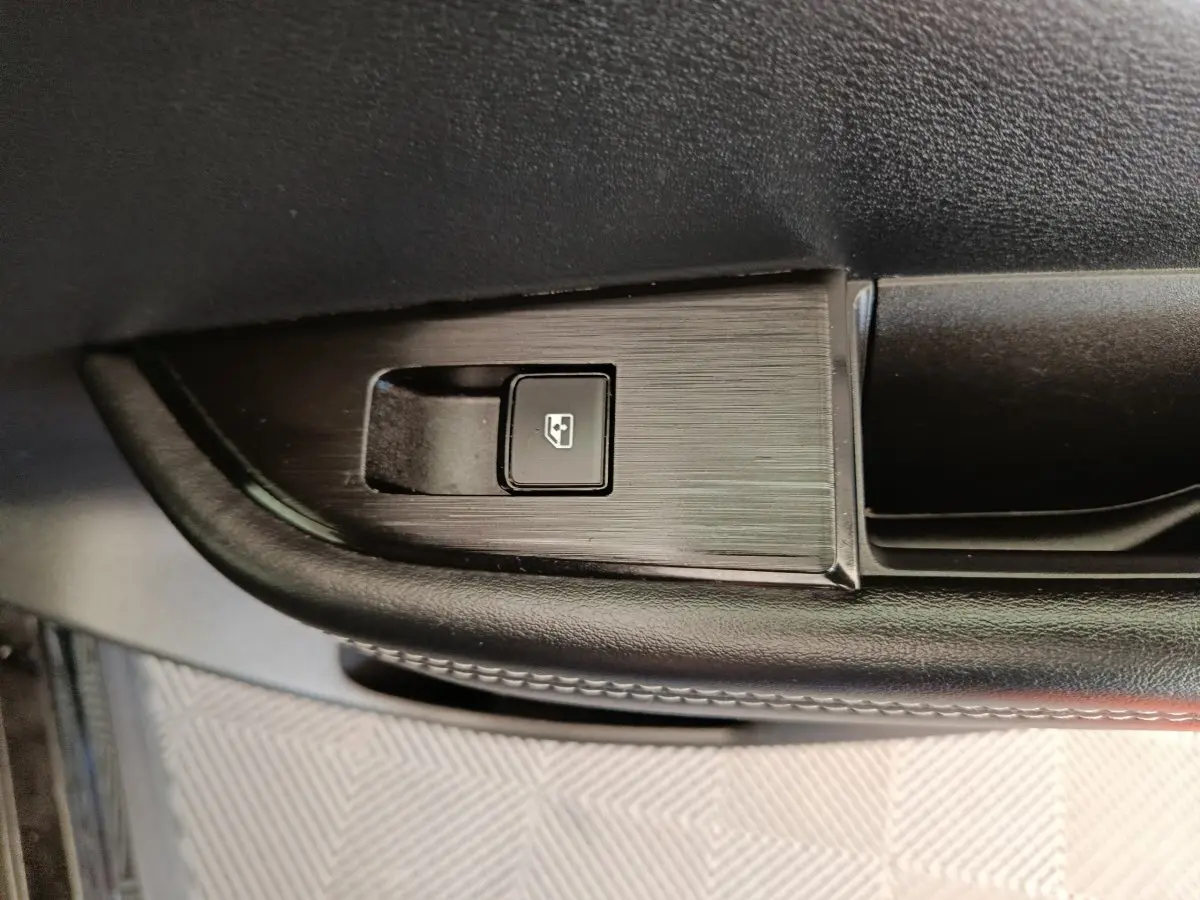 Bouton de lève-vitre électrique noir sur la porte intérieure côté conducteur du Nissan Qashqai e-Power 2024.