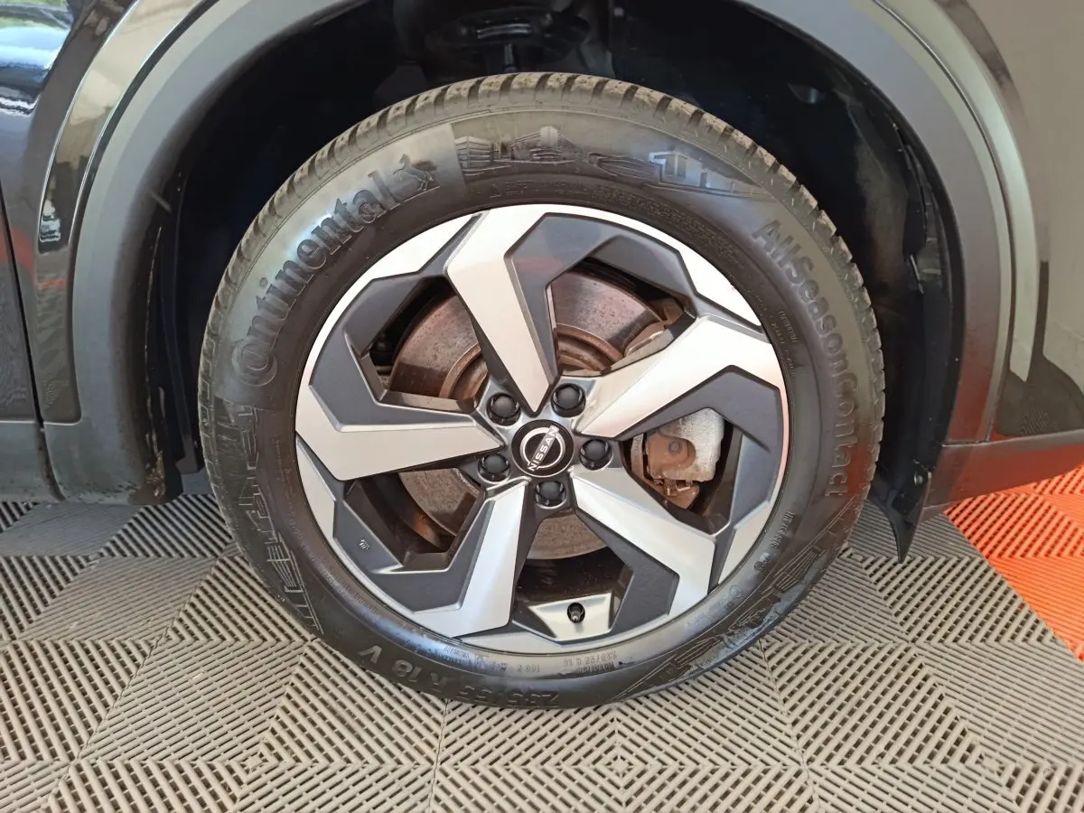 Gros plan sur la roue avant droite du Nissan Qashqai noir 2024 avec jante alliage bicolore et pneu Continental.