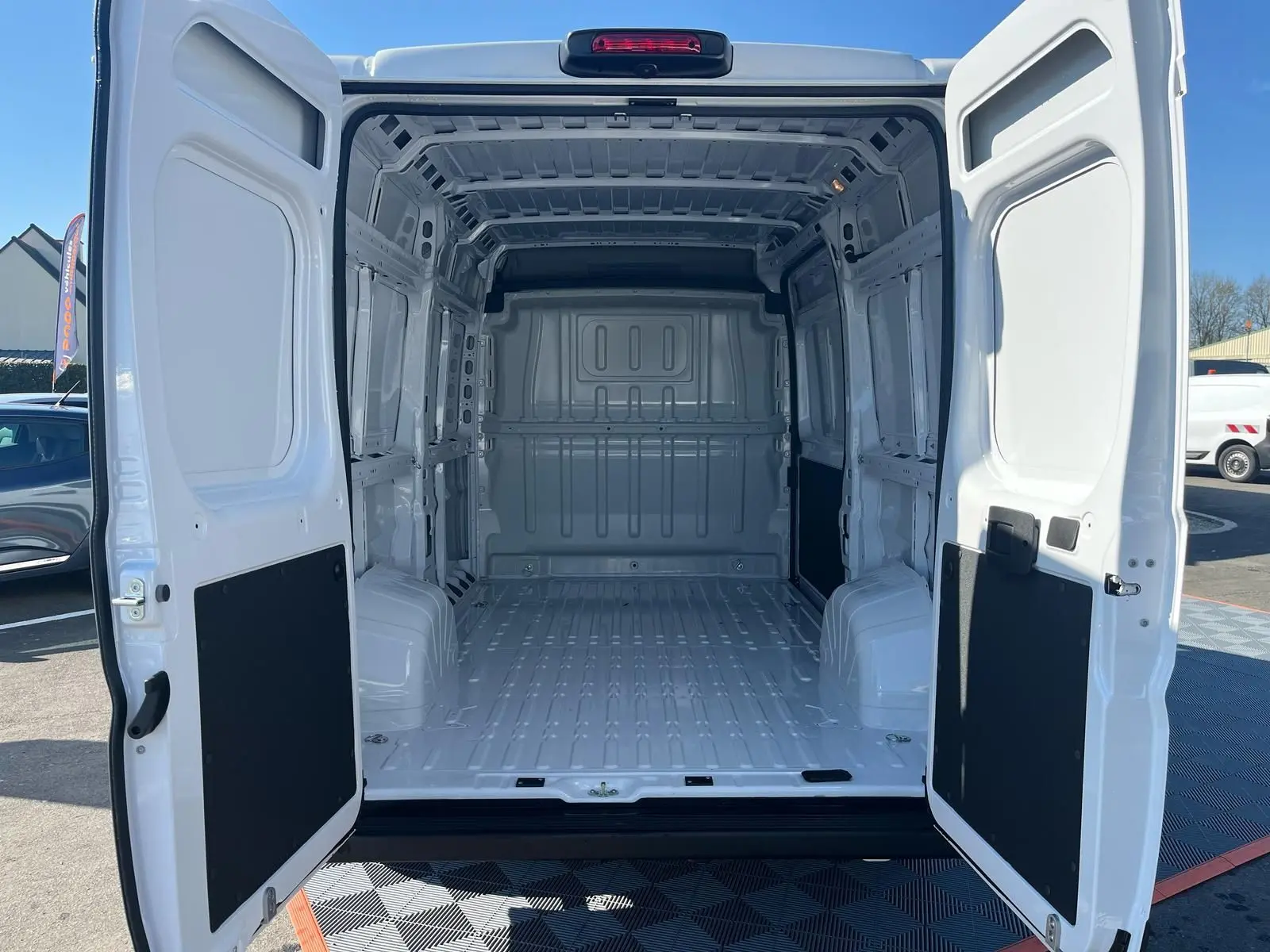 Vue arrière du FIAT Ducato Fourgon blanc 2023 avec portes ouvertes dévoilant l'espace de chargement vide et spacieux.