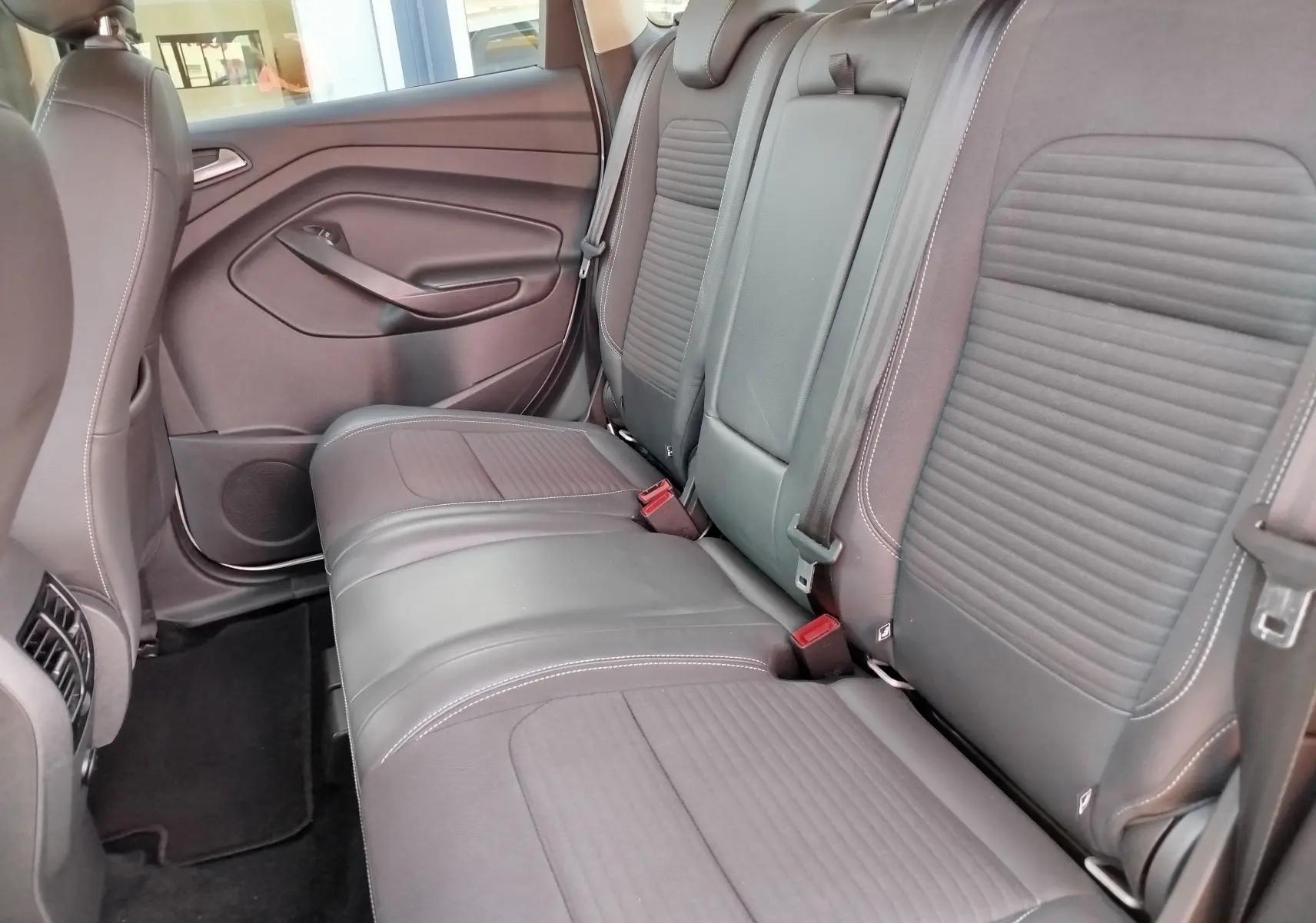 Vue latérale intérieure des sièges arrière gris foncé en tissu et cuir du Ford Kuga 2019, avec ceinture de sécurité visible.