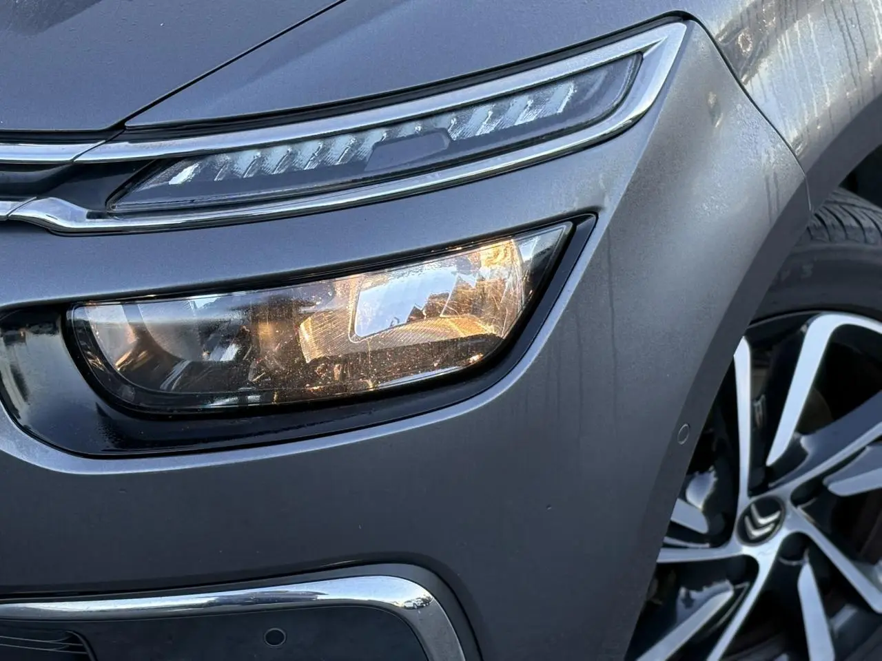 Gros plan sur l'avant droit gris Platinium d'une Citroën C4 Picasso 2017, avec phare LED et jante alliage bi-ton.