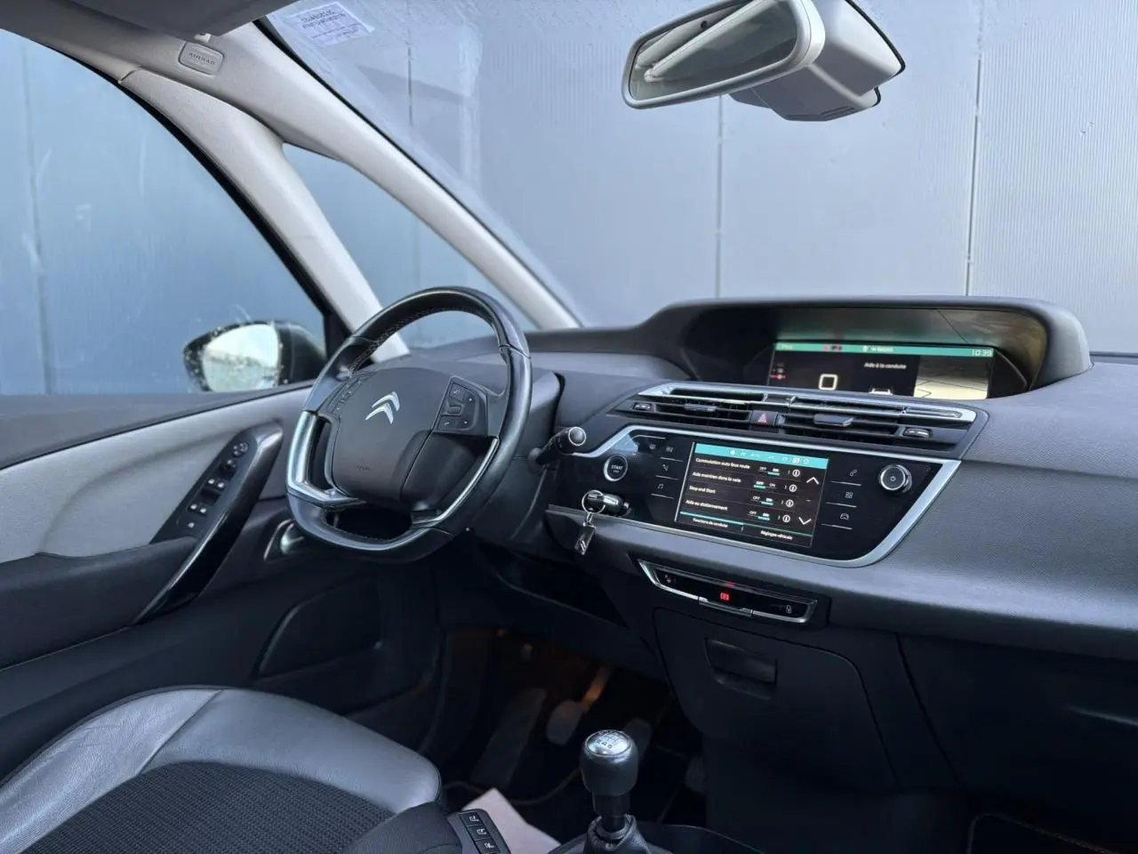 Intérieur de la Citroën C4 Picasso 2017 côté conducteur, tableau de bord noir avec écran tactile et volant cuir.