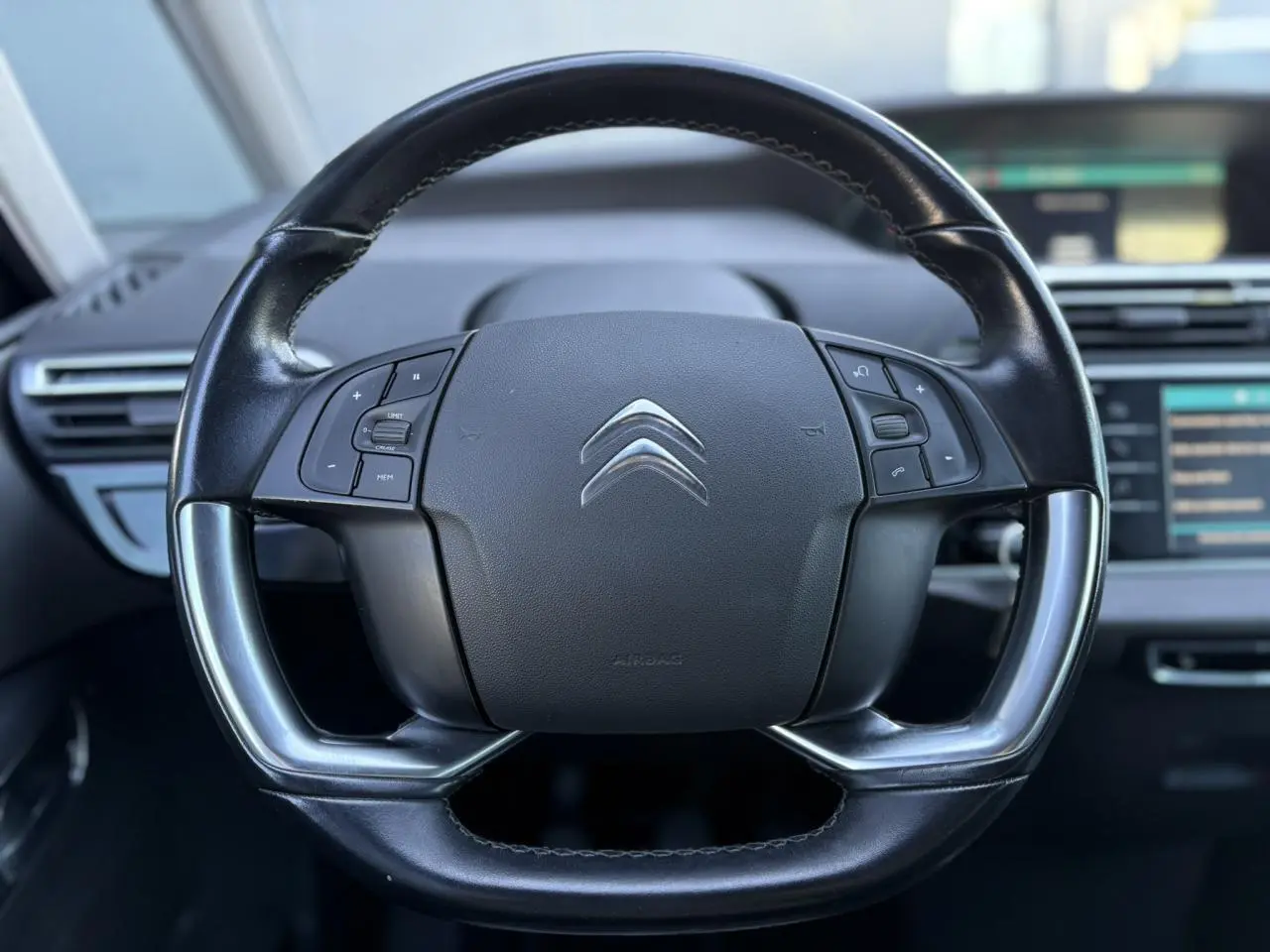 Gros plan sur le volant cuir noir du Citroën C4 Picasso 2017 avec commandes intégrées et logo chromé central.