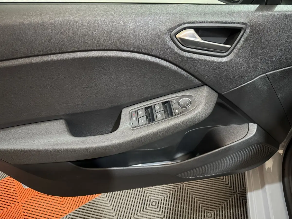 Vue rapprochée de la porte avant gauche grise de la Renault Clio 2025, avec commandes électriques des vitres et poignée argentée.
