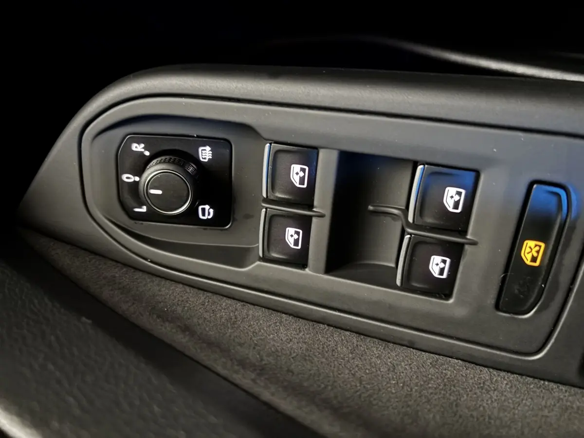 Gros plan sur les commandes des vitres et rétroviseurs côté conducteur d’une Volkswagen Golf noire 2024.