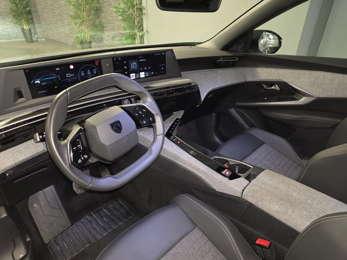Intérieur avant droit du Peugeot 3008 2025 hybride, avec tableau de bord numérique et sellerie tissu gris chiné.