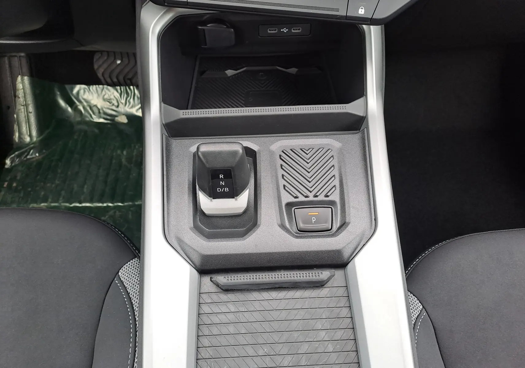 Vue plongeante sur la console centrale du Dacia Bigster Hybrid 155, avec levier de vitesses automatique et bouton de parking.