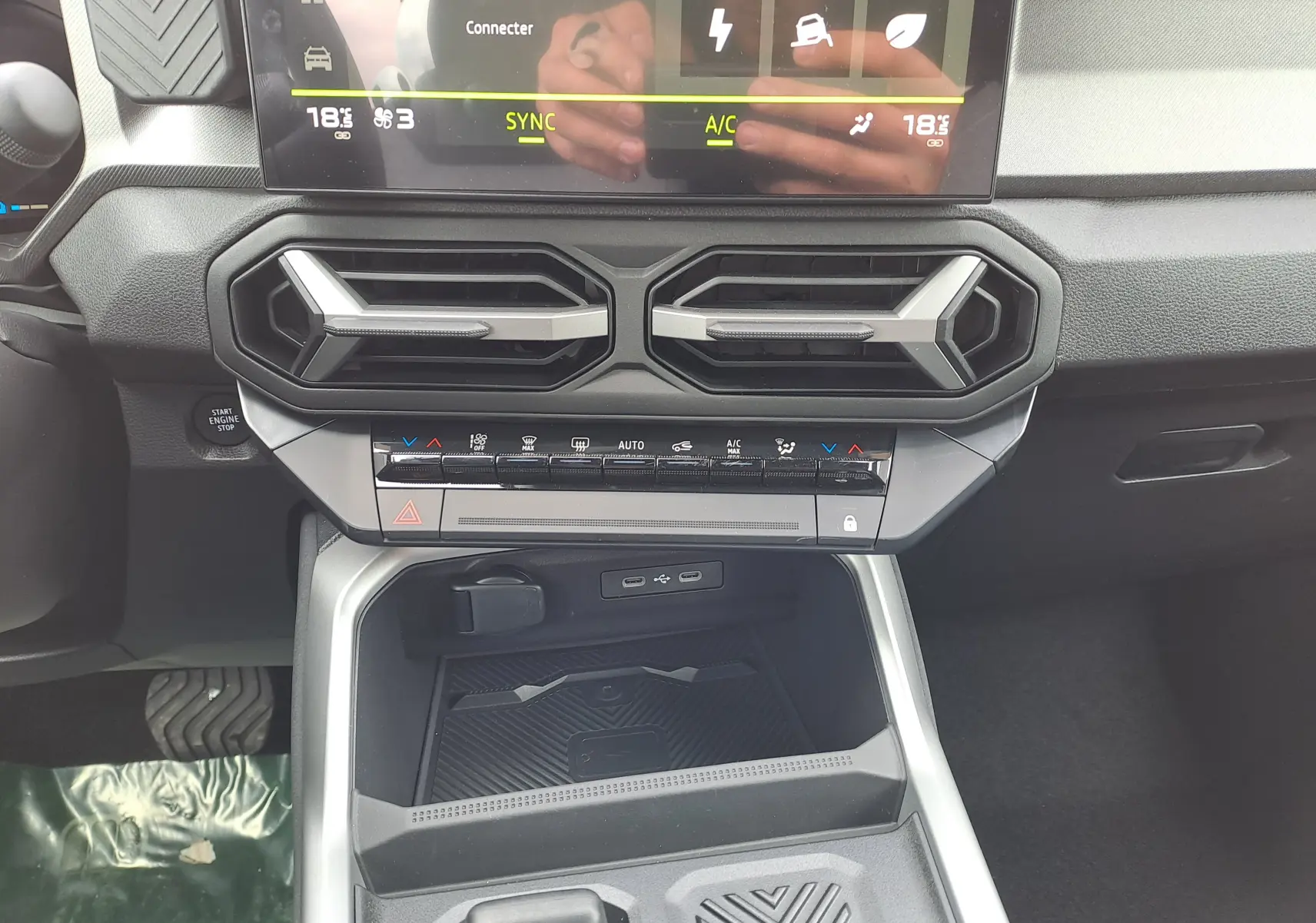 Détail du tableau de bord et console centrale du Dacia Bigster Hybrid 155, avec commandes climatisation et prises USB visibles.