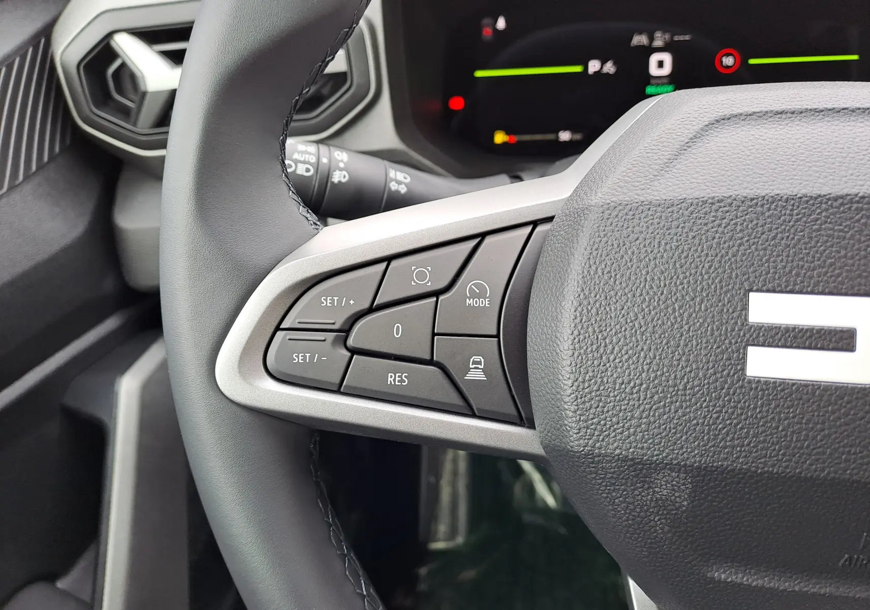 Gros plan sur la partie gauche du volant du Dacia Bigster 2026, avec commandes de régulateur et tableau de bord numérique en arrière-plan.