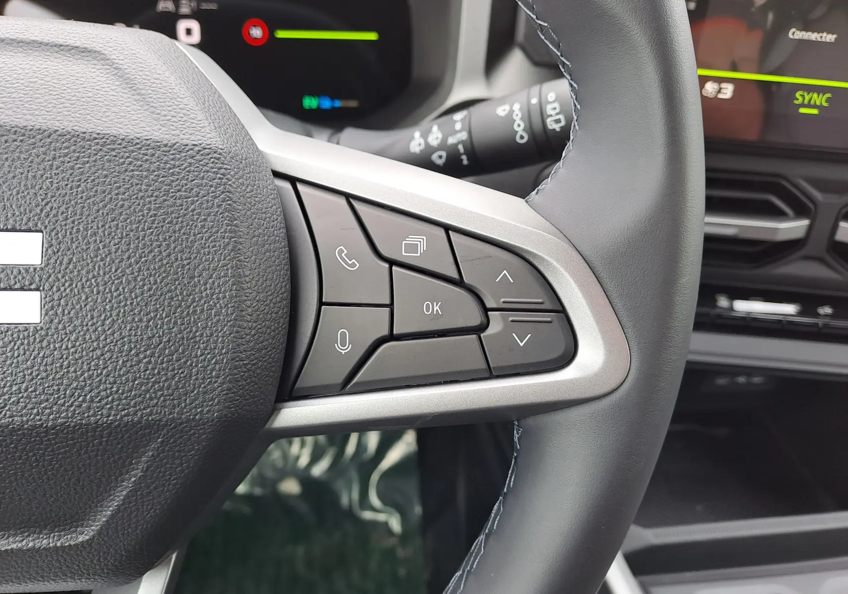 Gros plan sur les commandes au volant à droite du Dacia Bigster 2026, intérieur gris avec écran numérique en arrière-plan.