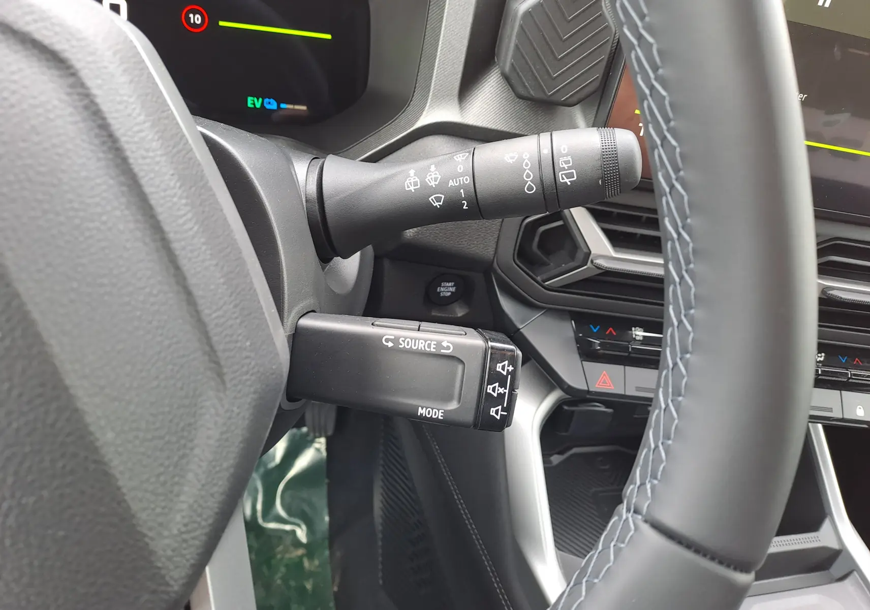 Gros plan sur la colonne de direction et commandes au volant du Dacia Bigster Hybrid 155, intérieur gris et détails noirs.