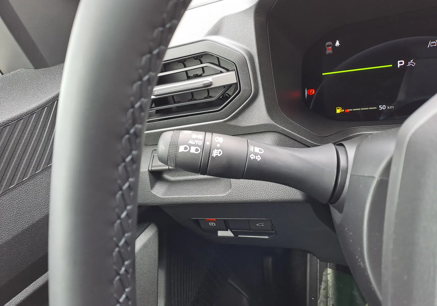 Gros plan sur la commande des phares et clignotants à gauche du volant dans le tableau de bord du Dacia Bigster vert cèdre.