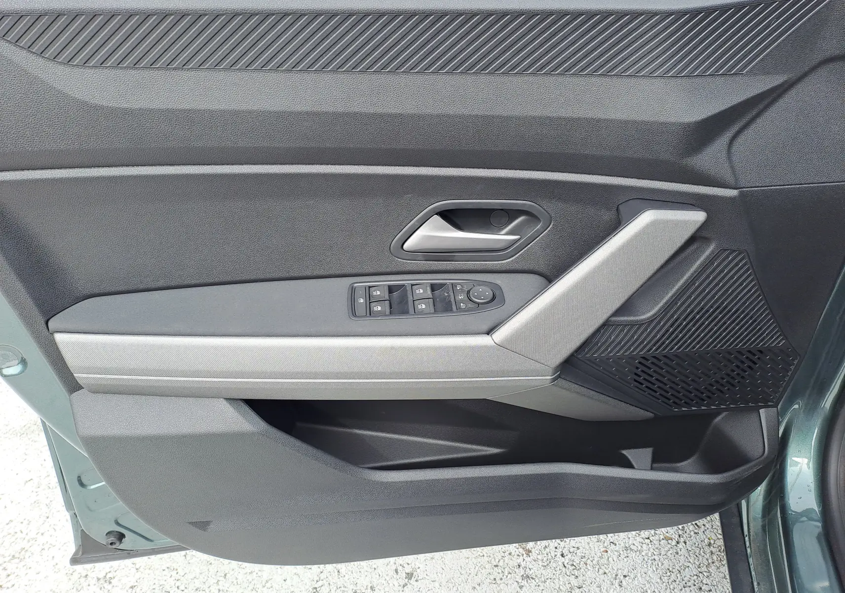 Vue rapprochée de la porte avant gauche du Dacia Bigster vert cèdre, avec commandes des vitres et poignée intégrée.