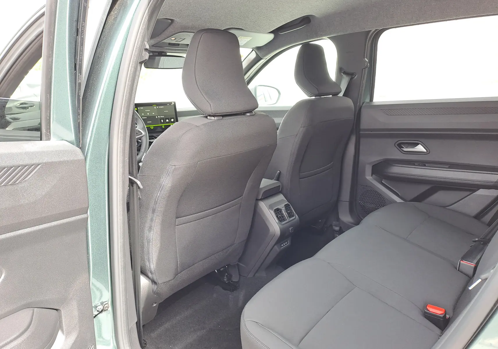 Vue intérieure arrière côté gauche du Dacia Bigster vert cèdre, montrant les sièges noirs et la console centrale avec aérateurs.