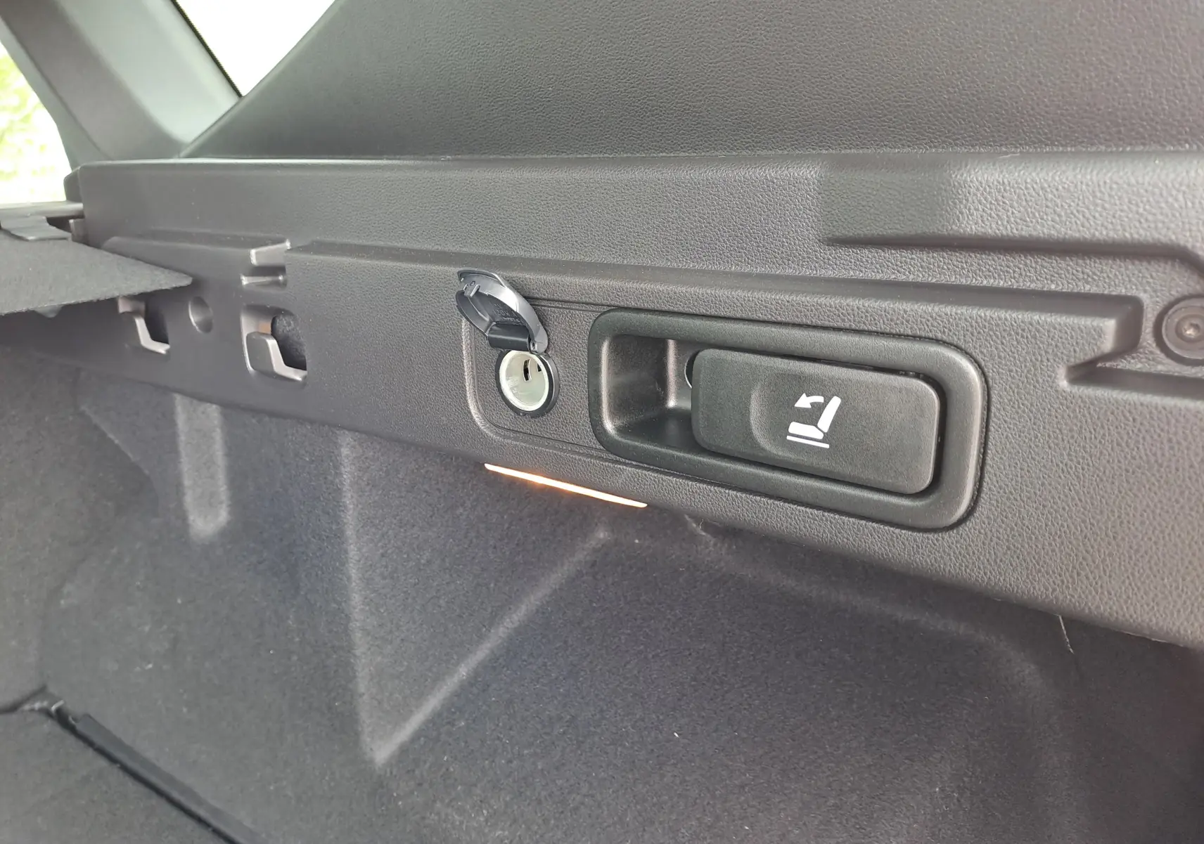 Gros plan sur la commande de rabattement des sièges dans le coffre du Dacia Bigster vert cèdre, version hybride 2026.