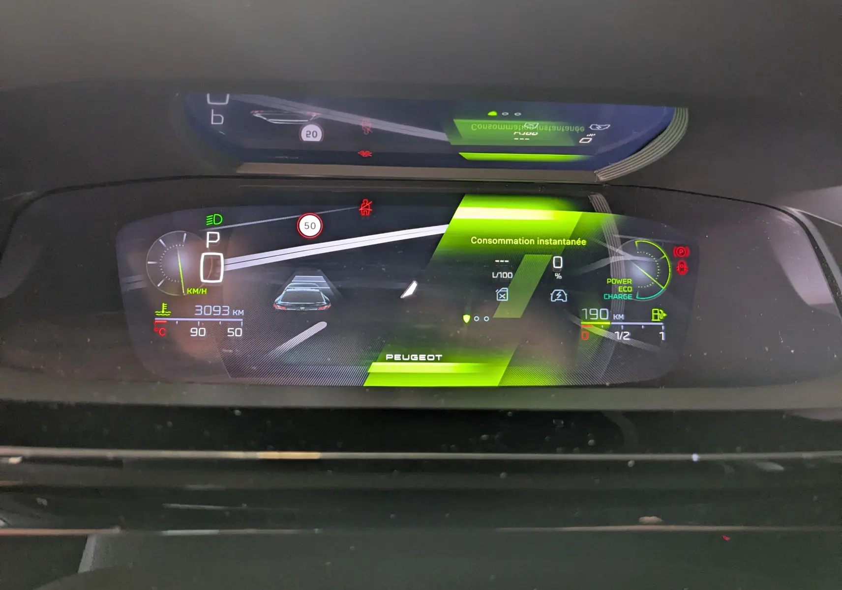 Affichage numérique du tableau de bord de la Peugeot 408 Hybrid 145 GT, montrant la consommation instantanée et l'autonomie.