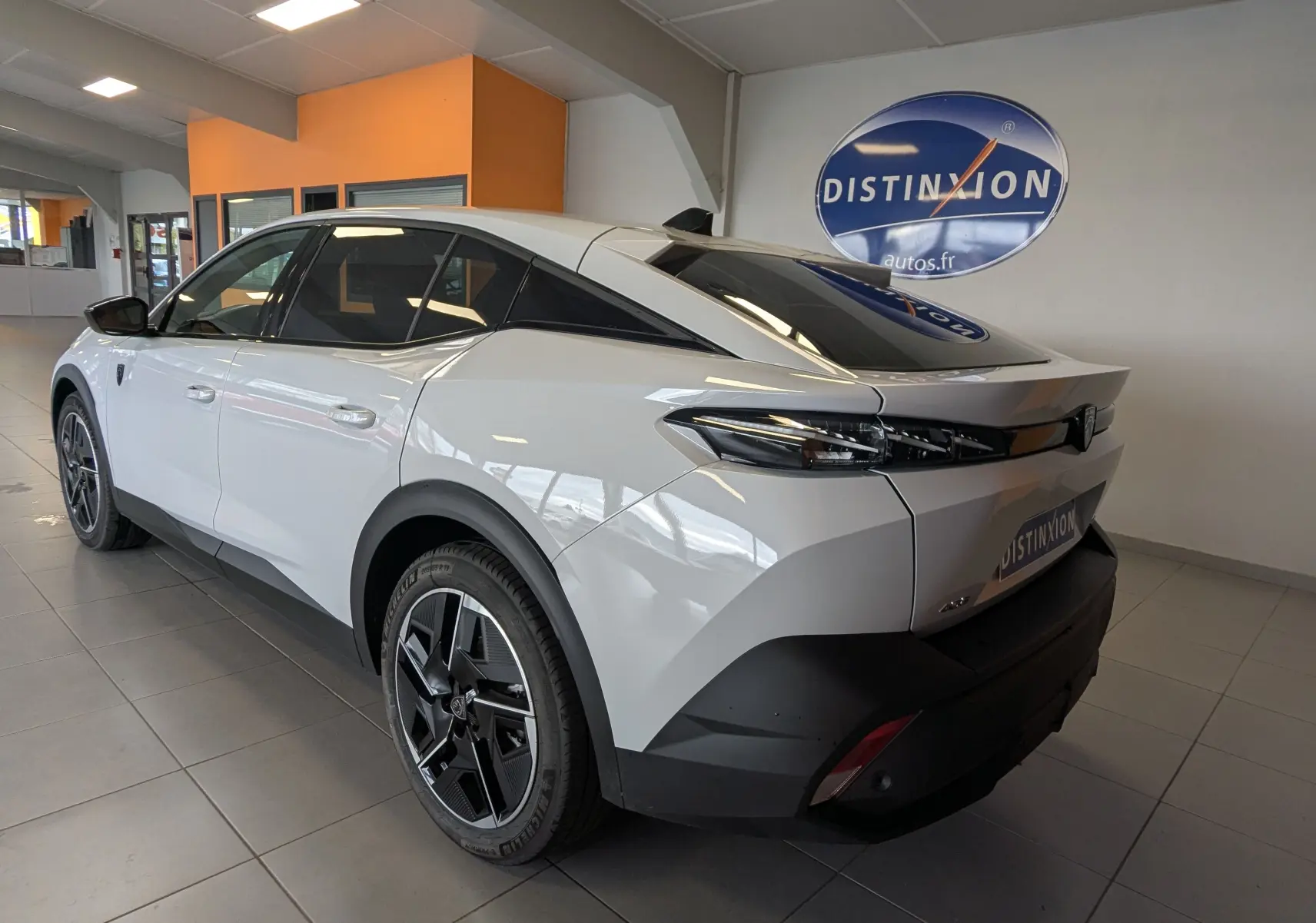 Peugeot 408 Hybrid 145 e-DCS6 GT blanc Okenite, vue 3/4 arrière droit en intérieur avec jantes alliage 19 pouces.