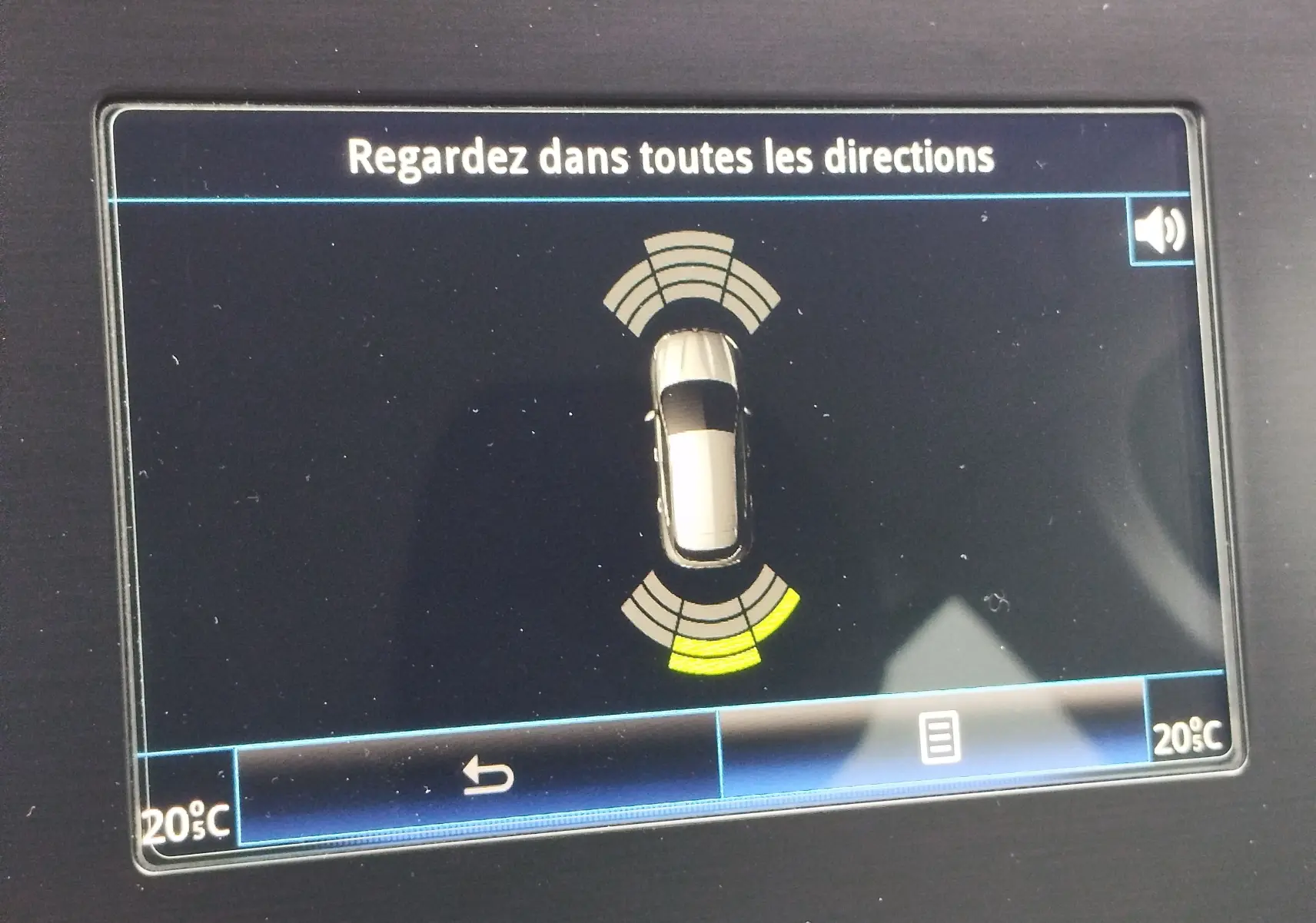 Écran de surveillance de proximité montrant une voiture grise vue de dessus avec alertes de stationnement avant et arrière.
