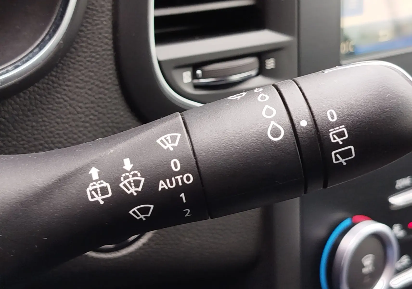 Gros plan sur la commande d’essuie-glace à gauche du volant dans l’habitacle d’une Renault Mégane gris titanium de 2018.