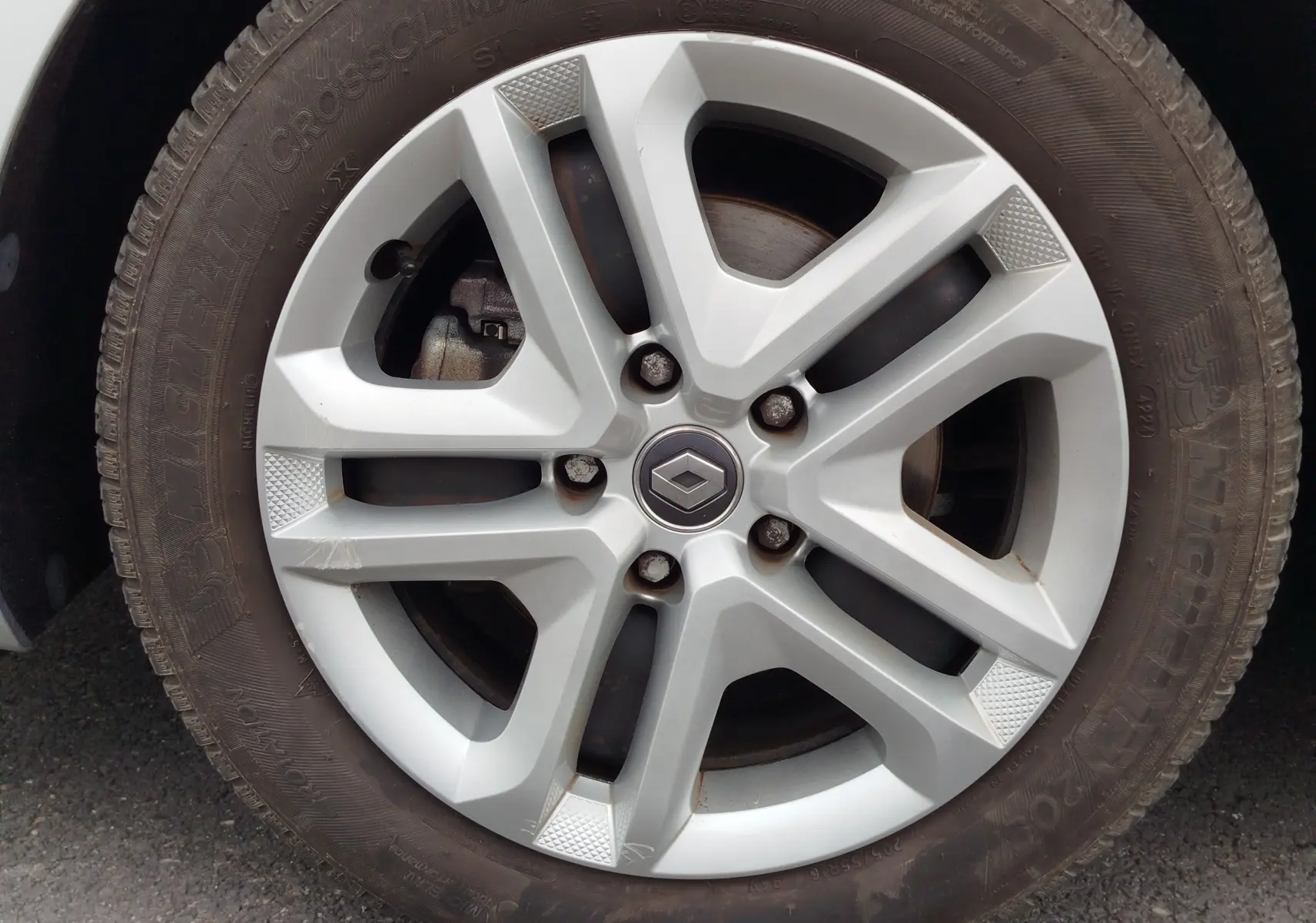 Gros plan sur la jante alliage argentée avec logo Renault au centre, montée sur un pneu Michelin d’une Renault Mégane gris titanium.