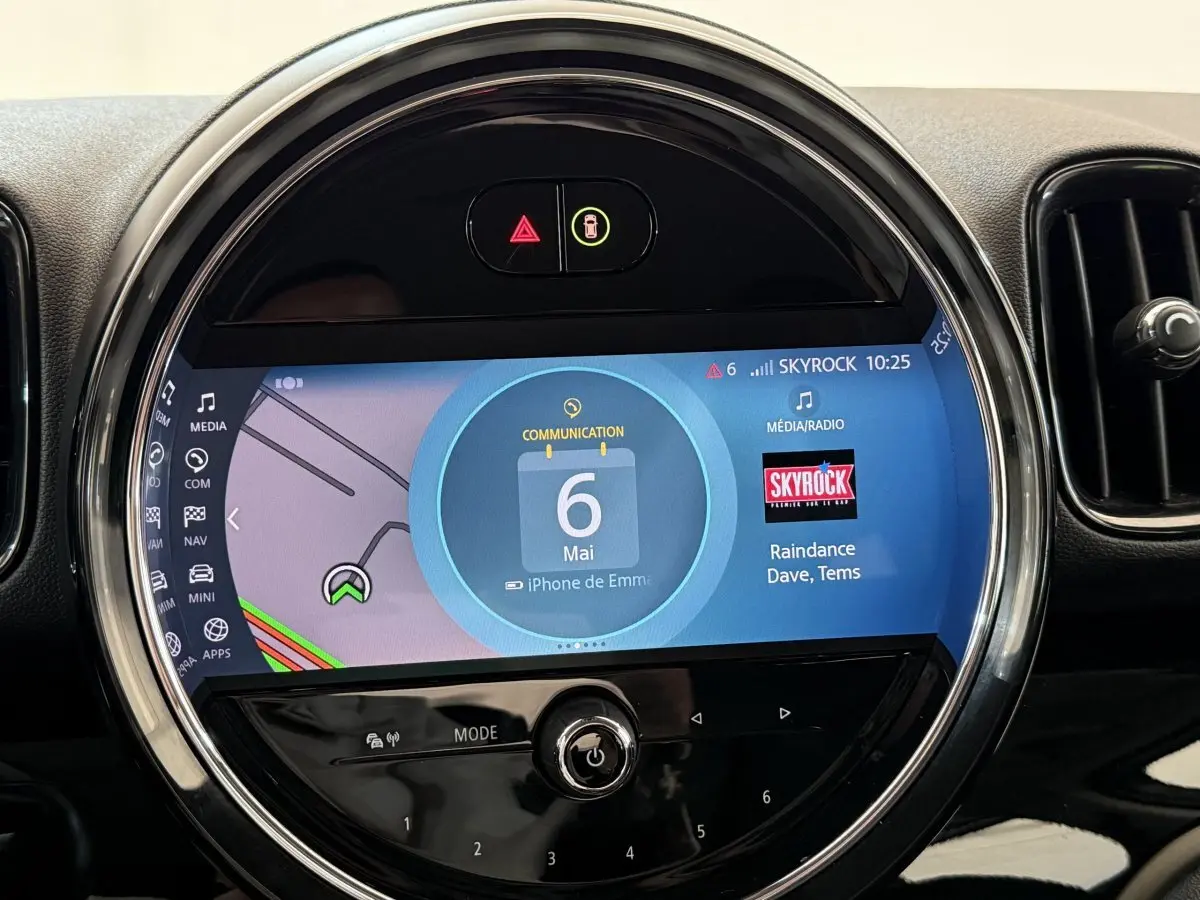 Gros plan sur l’écran tactile central rond du tableau de bord du MINI Countryman gris clair 2023, affichant la navigation et la radio.