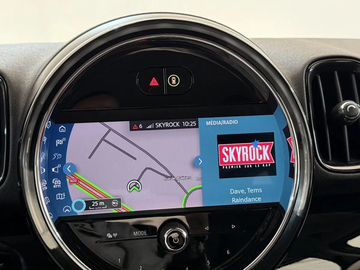 Écran tactile central rond du tableau de bord du MINI Countryman gris clair, affichant navigation et radio Skyrock.