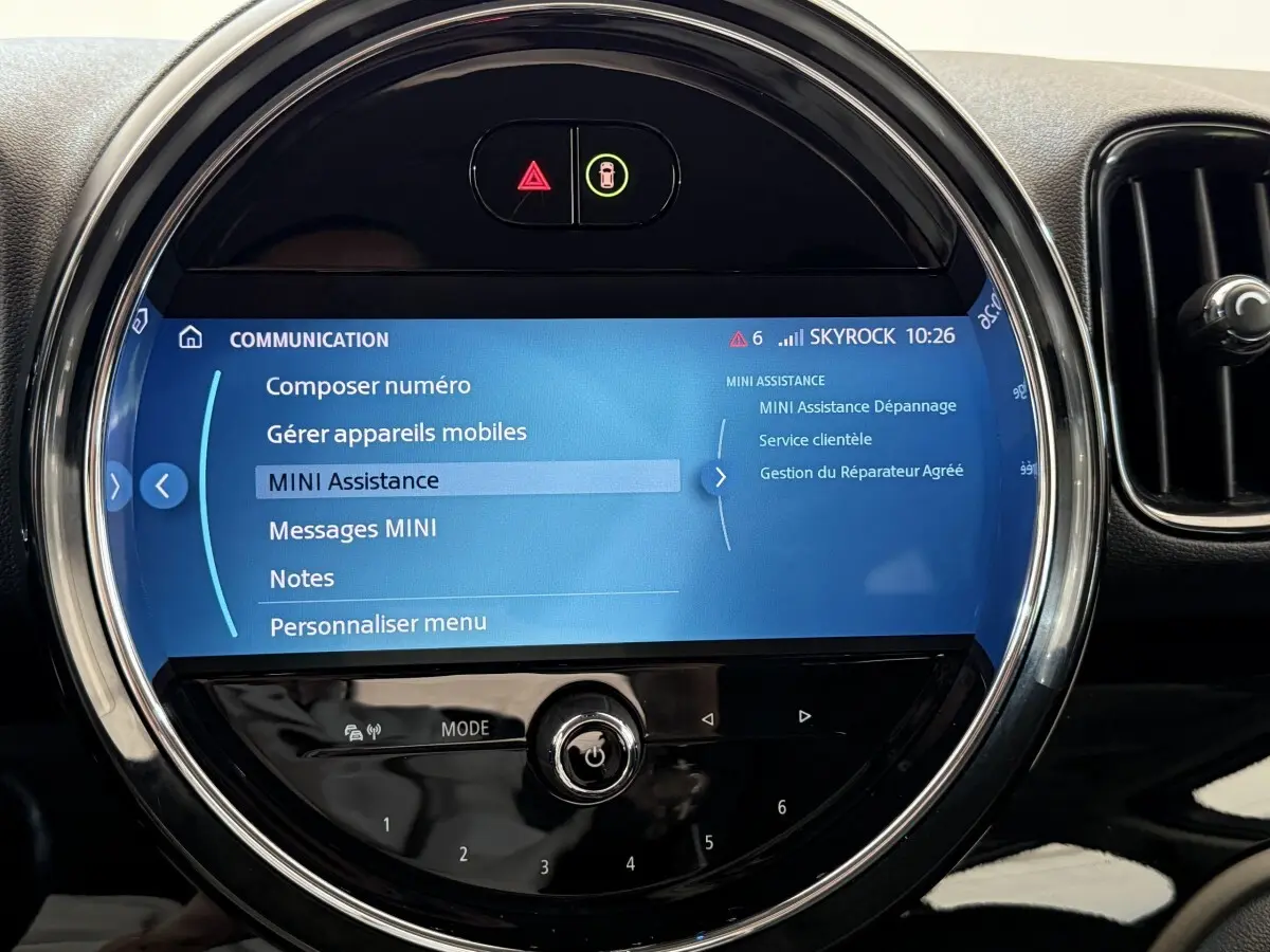 Gros plan sur l’écran tactile circulaire du tableau de bord du MINI Countryman gris clair, affichant le menu d’assistance.